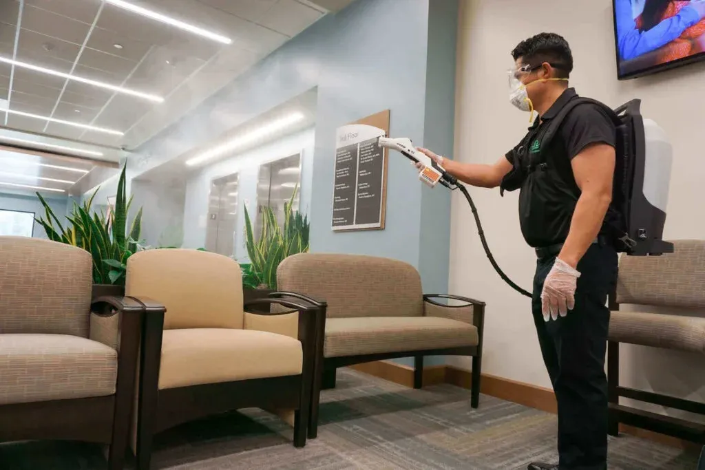 Green Sweep technician electrostatic-disinfecting a medical waiting room