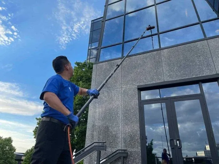 Green Sweep technician cleaning commercial windows with a pure-water pole